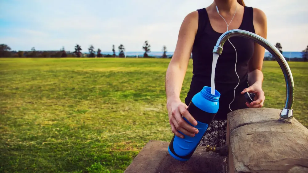 Person filled water bottle out of faucet in the middle of a field